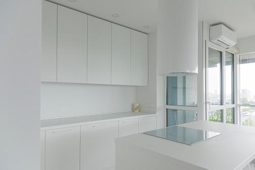a white kitchen with white cabinets and a window at VilniausPanorama in Vilnius