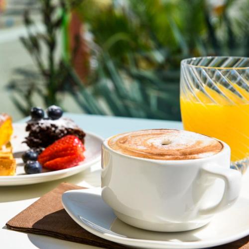a cup of coffee next to a plate of fruit at Baldinini Hotel in Rimini