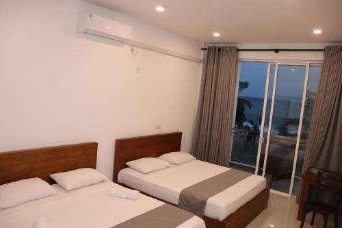 a hotel room with two beds and a window at Marakolliya Beach Resort in Tangalle