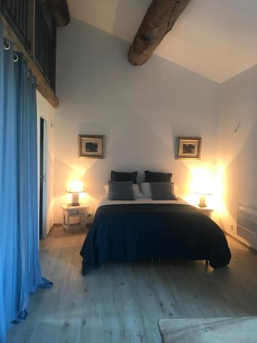 um quarto com uma cama grande e 2 candeeiros em L Ostalada em Roquefort-des-Corbières