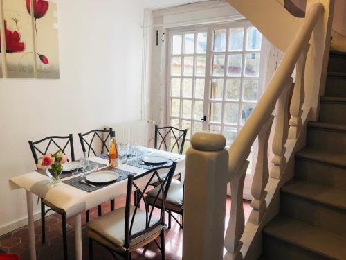 une salle à manger avec une table, des chaises et un escalier dans l'établissement La petite Normande en ville, à Louviers