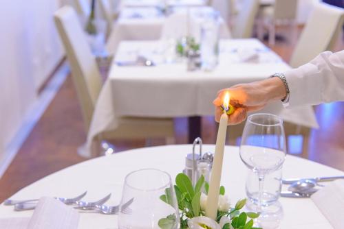 a person lighting a candle in a vase on a table at Hotel Cristallo in Riccione