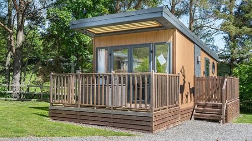a small cabin with a porch and a large window at Woodclose Park in Kirkby Lonsdale