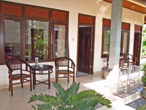 um pátio com uma mesa e cadeiras numa casa em Bucu Guest House em Ubud