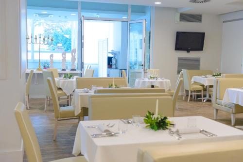 a restaurant with white tables and chairs and a television at Hotel Cristallo in Riccione