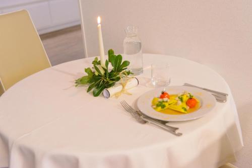 a white table with a plate of food and a candle at Hotel Cristallo in Riccione