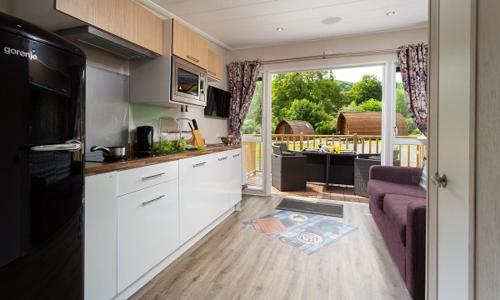 a kitchen with white cabinets and a purple couch at Woodclose Park in Kirkby Lonsdale