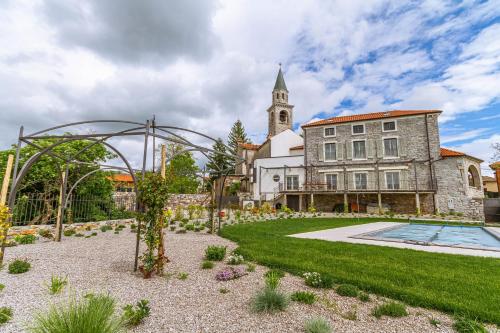a building with a garden and a church with a tower at Vila Brinovka in Kostanjevica na Krasu