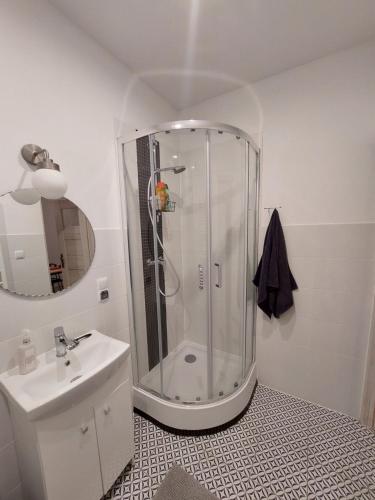 a white bathroom with a shower and a sink at Apartament Jedlinka in Jedlina-Zdrój