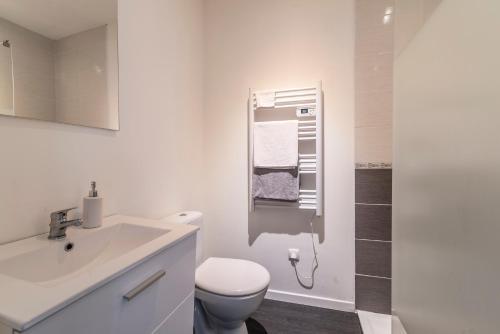 ein weißes Bad mit einem WC und einem Waschbecken in der Unterkunft Studio indépendant in Bétheny