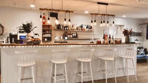 a bar with white stools in a room at Hotel Marie in Skagen