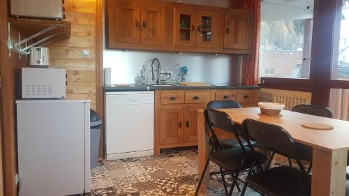 a kitchen with a table and chairs and a refrigerator at Plagne centre -Pied de pistes in La Plagne Tarentaise