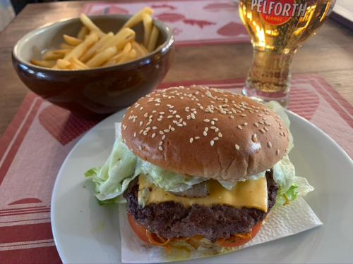 a hamburger on a plate next to a bowl of fries at La Chanterelle - Mountain Lodge in La Côte dʼArbroz