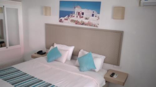 a bedroom with a bed with blue and white pillows at Hotel Atlal in Saïdia