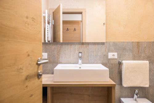 a bathroom with a white sink and a mirror at Rosalpina Apt 3 in San Vigilio Di Marebbe