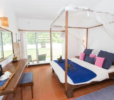 a bedroom with a canopy bed and a table at Sunbird Chintheche in Nkhata Bay