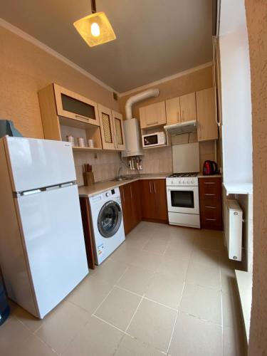 a kitchen with a white refrigerator and a dishwasher at Апартаменты на проспекте in Vinnytsya