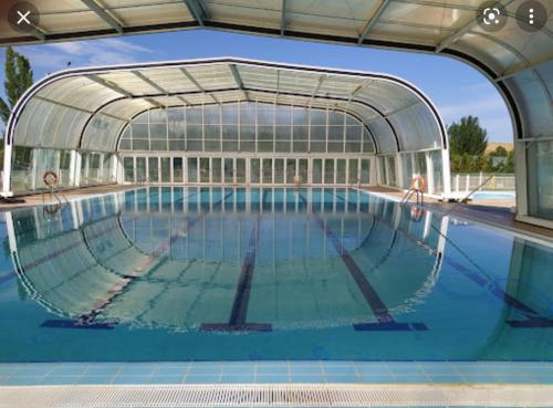 uma piscina com um grande edifício de vidro em Rioja Martín em Alba de Tormes