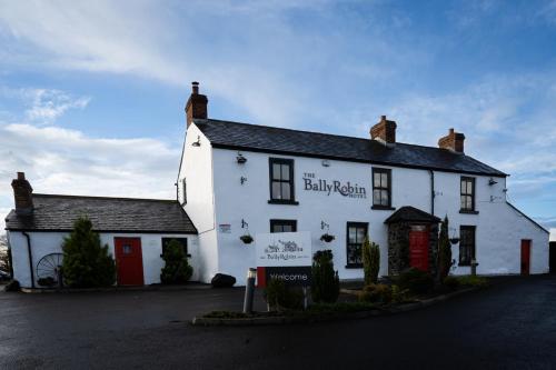 a white building with a red door on a street at Ballyrobin Hotel in Aldergrove