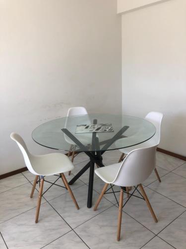 a glass table with four white chairs around it at Abdon Batista - Apto completo central, Smart TV in Joinville