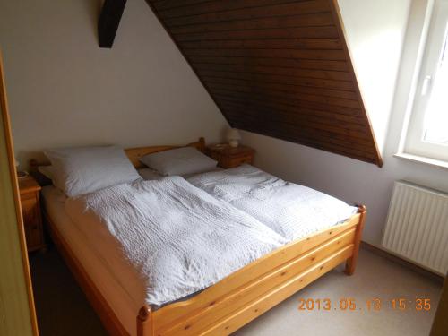 Schlafzimmer mit einem Bett mit einem Holzrahmen und einem Fenster in der Unterkunft Gasthaus Wollmeiner in Schmallenberg