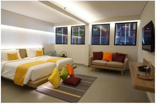 - une chambre avec un lit, un canapé et des fenêtres dans l'établissement QUBIKA BOUTIQUE HOTEL, à Tangerang
