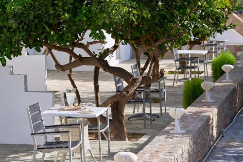 a row of tables and chairs under a tree at Santa Maria Village Resort & Spa in Adamas