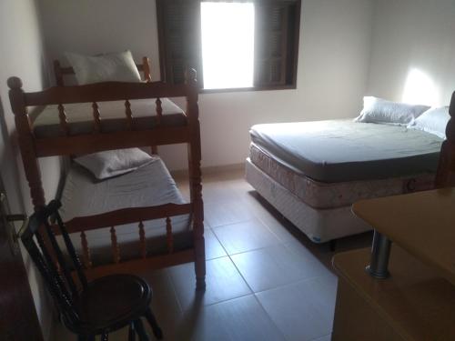 a room with two beds and a chair and a window at Casa de praia Indaiá Bertioga in Bertioga