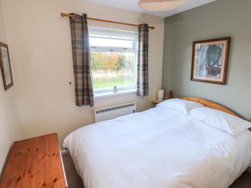 a bedroom with a white bed and a window at Bayview Bungalow in Swansea