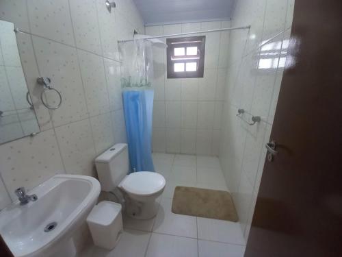 uma casa de banho com um WC, um chuveiro e um lavatório. em Casa de praia Indaiá Bertioga em Bertioga