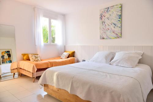 a white bedroom with a bed and a chair at L’appartement - Jardin Secret in Marseille