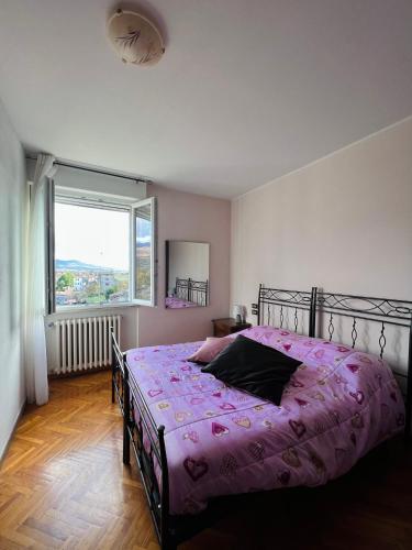 a bedroom with a bed with a pink comforter and a window at B&B del Lago in Sansepolcro