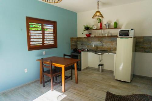 a kitchen with a table and a refrigerator in a room at Pipa Family House in Pipa