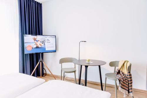 a living room with a tv and a table and chairs at THE FLAG Meiller Gärten in Munich