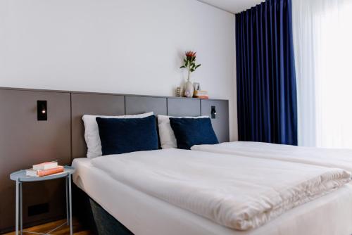 a bedroom with two beds with blue pillows at THE FLAG Meiller Gärten in Munich