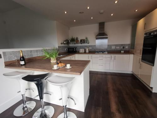 a kitchen with white cabinets and a counter with stools at Tiger House Luxury Riverside Home in Stockton-on-Tees