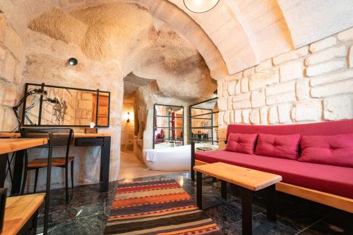 a living room with a red couch and a stone wall at Agarta Cave Hotel in Goreme
