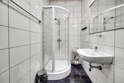 ein weißes Bad mit einer Dusche und einem Waschbecken in der Unterkunft ARTAPART.ART Hotel in Sankt Petersburg
