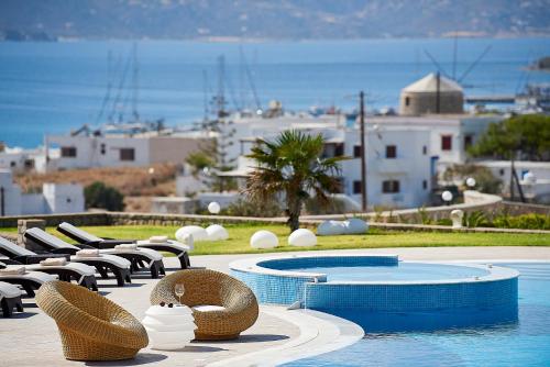 a swimming pool with wicker chairs next to a resort at Santa Maria Village Resort & Spa in Adamas