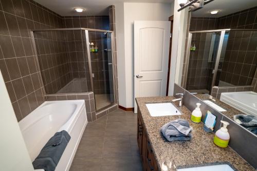 a bathroom with a tub and a shower and a sink at The Raven Suite at Stoneridge Mountain Resort in Canmore