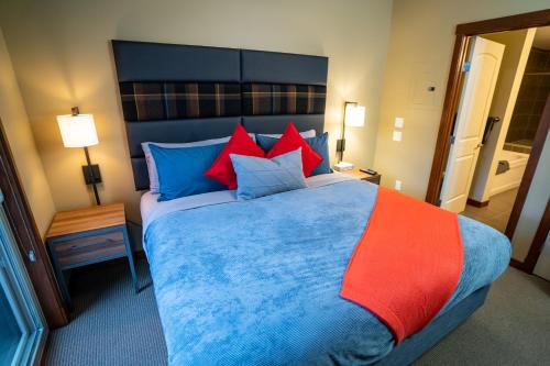 a bedroom with a large bed with blue and red pillows at The Raven Suite at Stoneridge Mountain Resort in Canmore