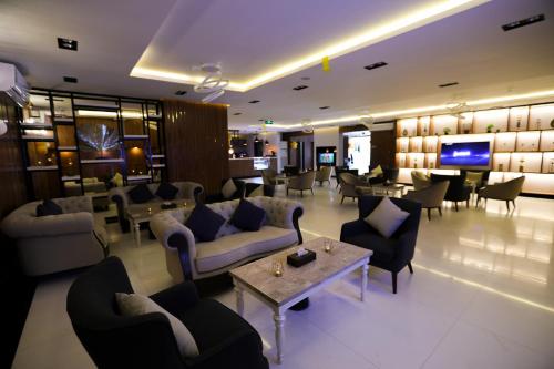 a hotel lobby with couches and tables and a television at جراند سيزون للشقق المخدومة in Dammam