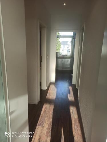 an empty hallway with a window and a wooden floor at Sky Night City Appartment in Düren - Eifel