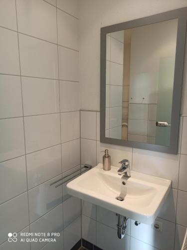 a white bathroom with a sink and a mirror at Sky Night City Appartment in Düren - Eifel