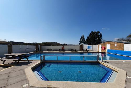 a swimming pool with a table and a picnic table at Llanrhidian Holiday Park in Llanmorlais