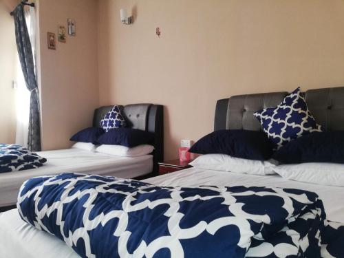 プチョンにあるCosy P6 Homestayの青と白の枕が備わる客室内のベッド2台