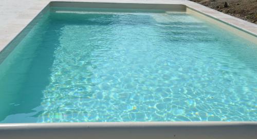 a swimming pool with blue water in a yard at Chez Madeleine in Saint-Colomb-de-Lauzun