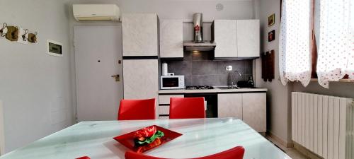 a small kitchen with a table and red chairs at GUEST HOLIDAY BARI in Reggio Emilia
