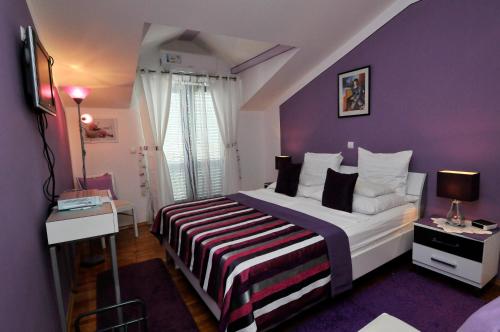 una camera con un grande letto con una parete viola di Hotel Haus Am Meer Cavtat a Cavtat