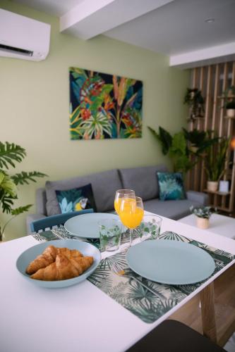 une table avec deux assiettes de nourriture et un verre de jus d'orange dans l'établissement Appartement climatisé - Vert Nature - hyper-centre de Toulon, à Toulon